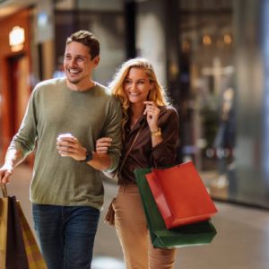 Smiling young couple walking through the mall after some shopping